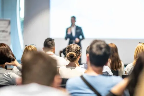 Male speaker giving a talk in conference hall at business event. Audience at the conference hall. Business and Entrepreneurship concept. Focus on unrecognizable people in audience. | FREE ONLINE STEEL BRIDGE LIVE LECTURE SERIES TO BE HELD SEPTEMBER 13-29, 2022